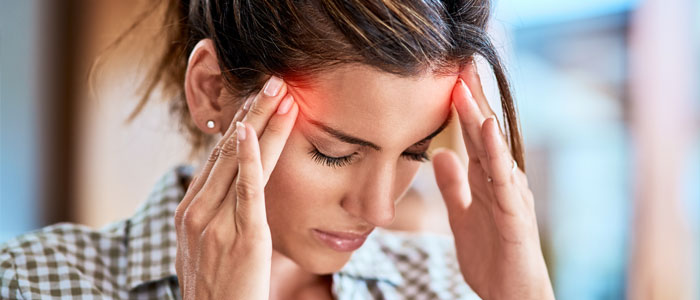 woman with a headache holding her temples in pain